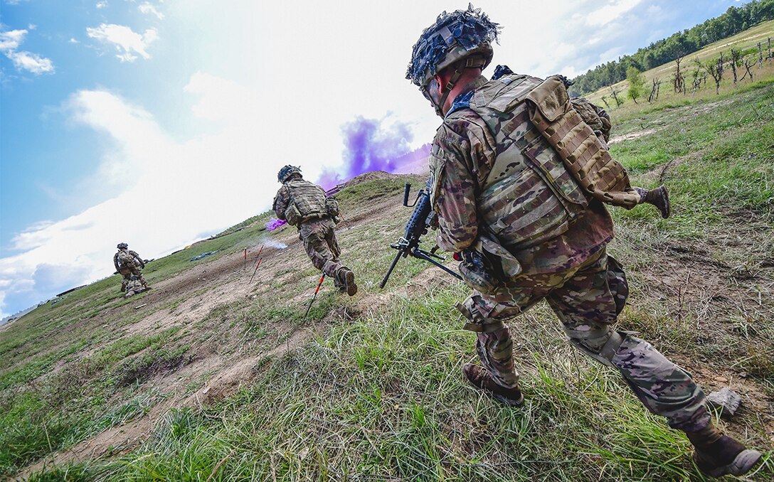 Soldiers run across a field.