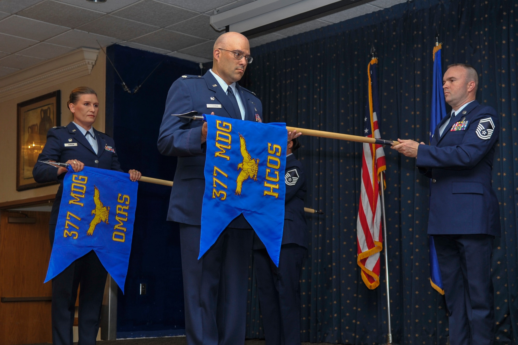 Guidons belonging to the 377th Operational Medical Readiness Squadron and the 377th Health Care Operations Squadron are unfurled in a redesignation ceremony at Kirtland Air Force Base, N.M., August 16, 2019. The redesignation ceremony is part of military history dating back to the 18th century during the reign of King Frederick the Great of Prussia. During this time, organizational flags were developed with color arrangement and symbols unique to a particular unit. (U.S. Air Force photo by Airman 1st Class Austin J. Prisbrey)