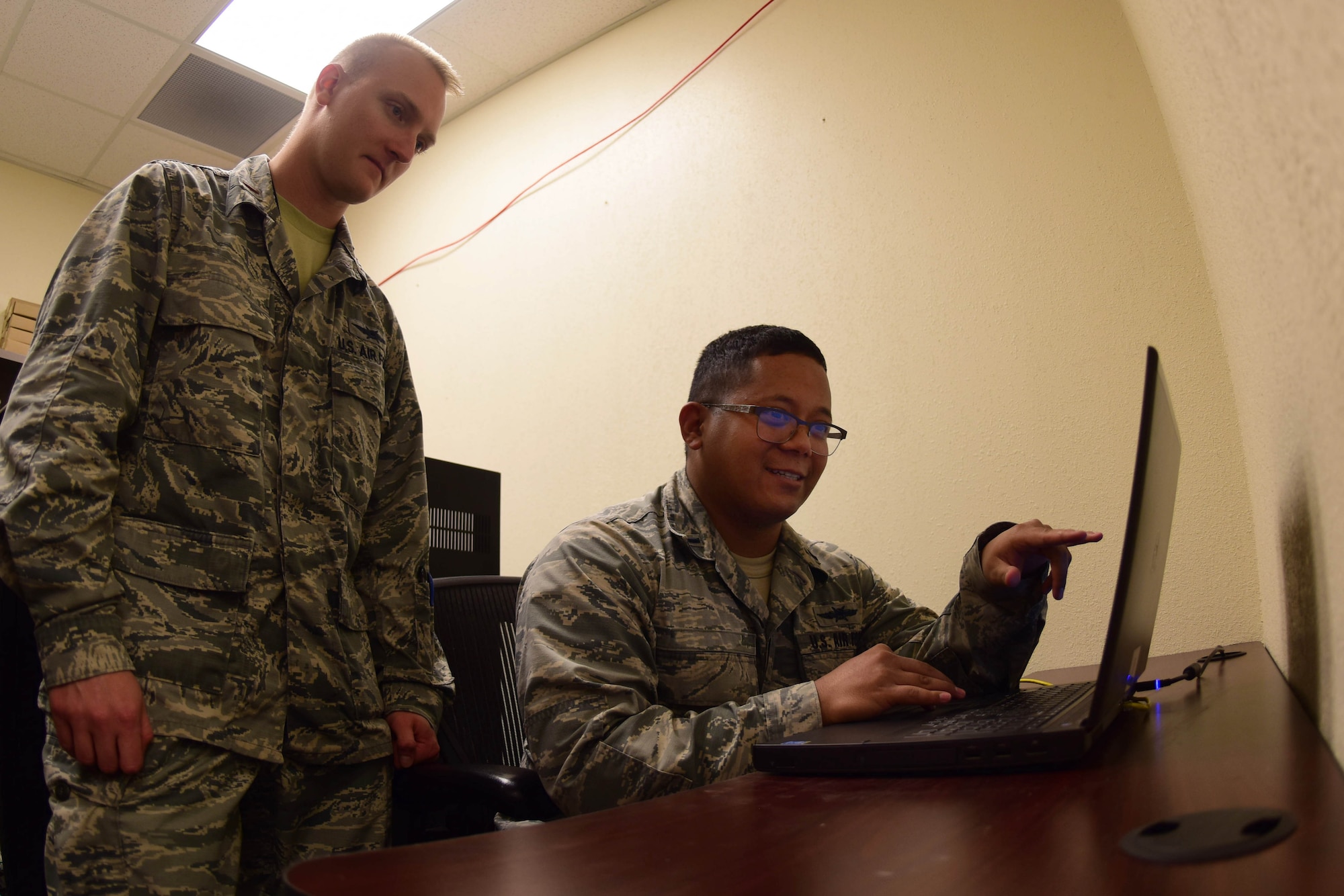1st Lt. Vaughn, 432nd Aircraft Communications Maintenance Squadron Mission Defense Team officer in charge, and 2nd Lt. Eric, 432nd ACMS MDT Assistant officer in charge, go over computer code at Creech Air Force Base, Nevada, April 29, 2019. The 432nd Wing’s MDT is tasked with assuring the integrity of the MQ-9 Reaper’s cyber networks and protecting the support equipment that connect the aircraft to the cockpits on the ground. (U.S. Air Force photo by Airman 1st Class Haley Stevens)