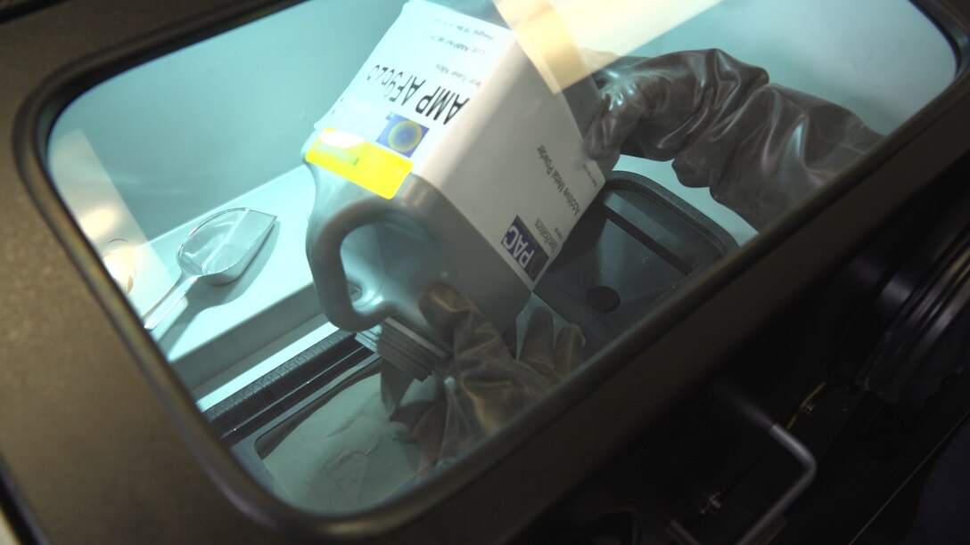 Capt. Erin Hager pours the powdered form of AF-9628 steel into a powder bed fusion machine. In this type of additive manufacturing, a laser selectively melts powder in a pattern to create three-dimensional objects. As each layer is complete, the printer dispenses more powder on the build area, and the process continues until the part is complete. Once Hager verified that the powder melted predictably in the machine, she began creating actual test articles. (Courtesy photo/Air Force Institute of Technology)