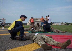 Members assigned to the 733d Civil Engineer Division assess patient injuries during an aircraft crash exercise at Joint Base Langley-Eustis, Virginia, Aug. 13, 2019.