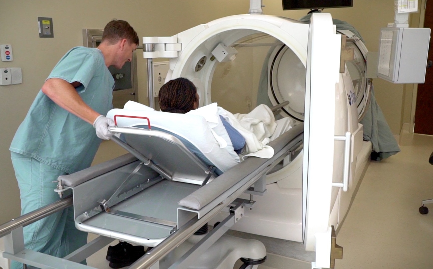 A staff member places a patient into the single hyperbaric oxygen chamber at the Undersea & Hyperbaric Medicine Clinic at Brooke Army Medical Center. Hyperbaric oxygen is an intervention in which an individual breathes nearly 100 percent oxygen while inside a hyperbaric chamber that is pressurized to greater than sea level pressure.