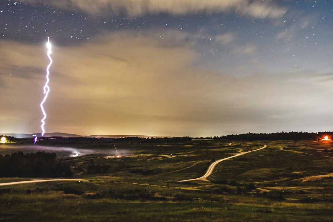 A wide open field at night with a missile launching into the sky.