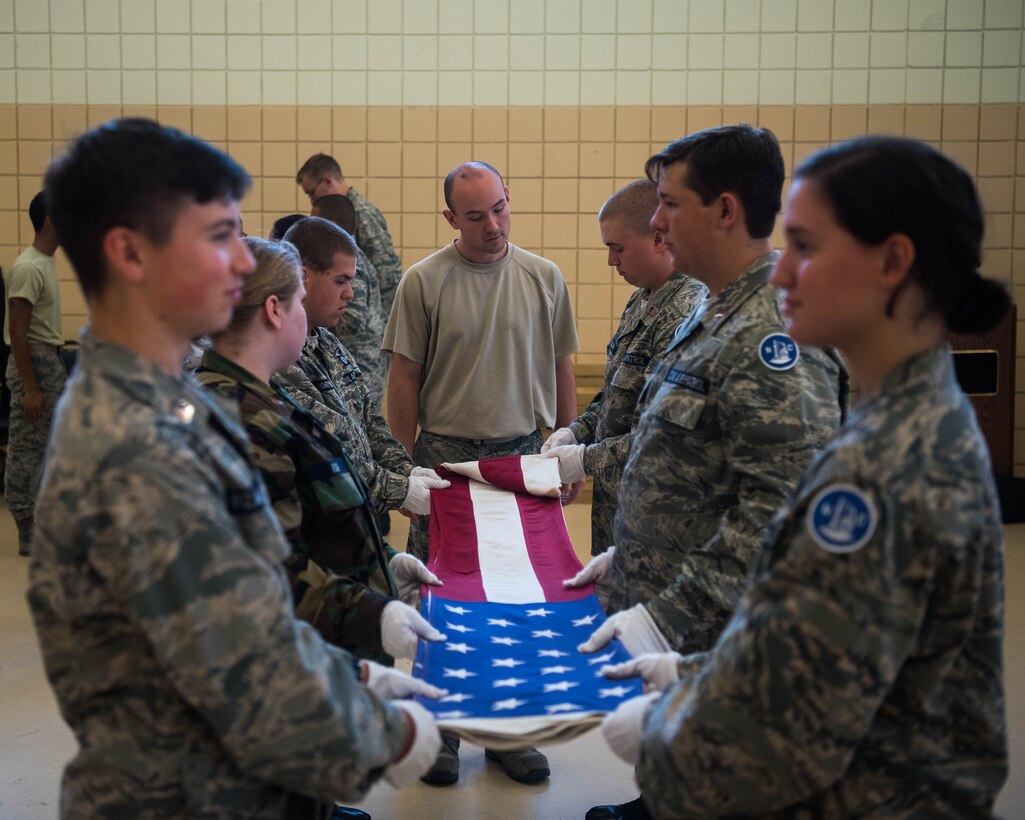 A member of the Langley Honor Guard educates members of the Civil Air Patrol on how to properly fold the U.S. Flag at Joint Base Langley-Eustis, Virginia, July 17, 2019. Members of CAP from all over the U.S. were taught different procedures from the Honor Guard including presenting the U.S. flag at ceremonies, folding the U.S. Flag at a memorial service or properly placing a wreath during a ceremony. (U.S. Air Force photo by Airman 1st Class Marcus M. Bullock)