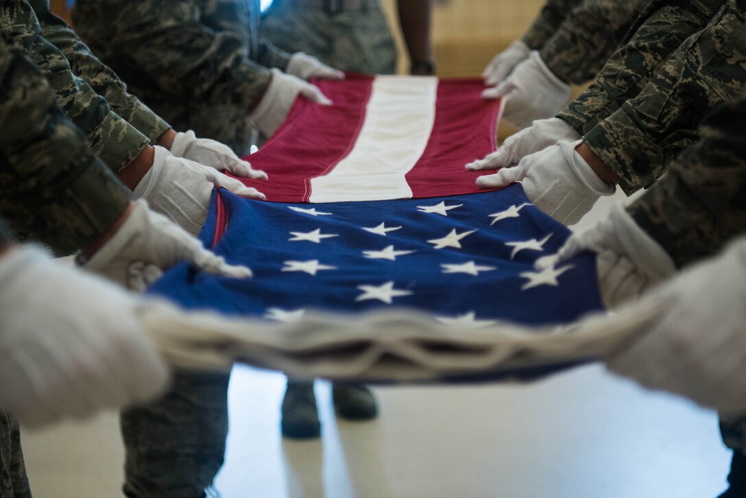 Members of the Civil Air Patrol fold the U.S. Flag at Joint Base Langley-Eustis, Virginia, July 17, 2019. CAP cadets who graduate from the Mid-Atlantic Honor Guard Academy have earned the right to wear the Honor Guard Academy patch on their Airman’s Battle Dress Uniform, and also a National Cadet Special Activities ribbon on their Blues Uniform. (U.S. Air Force photo by Airman 1st Class Marcus M. Bullock)