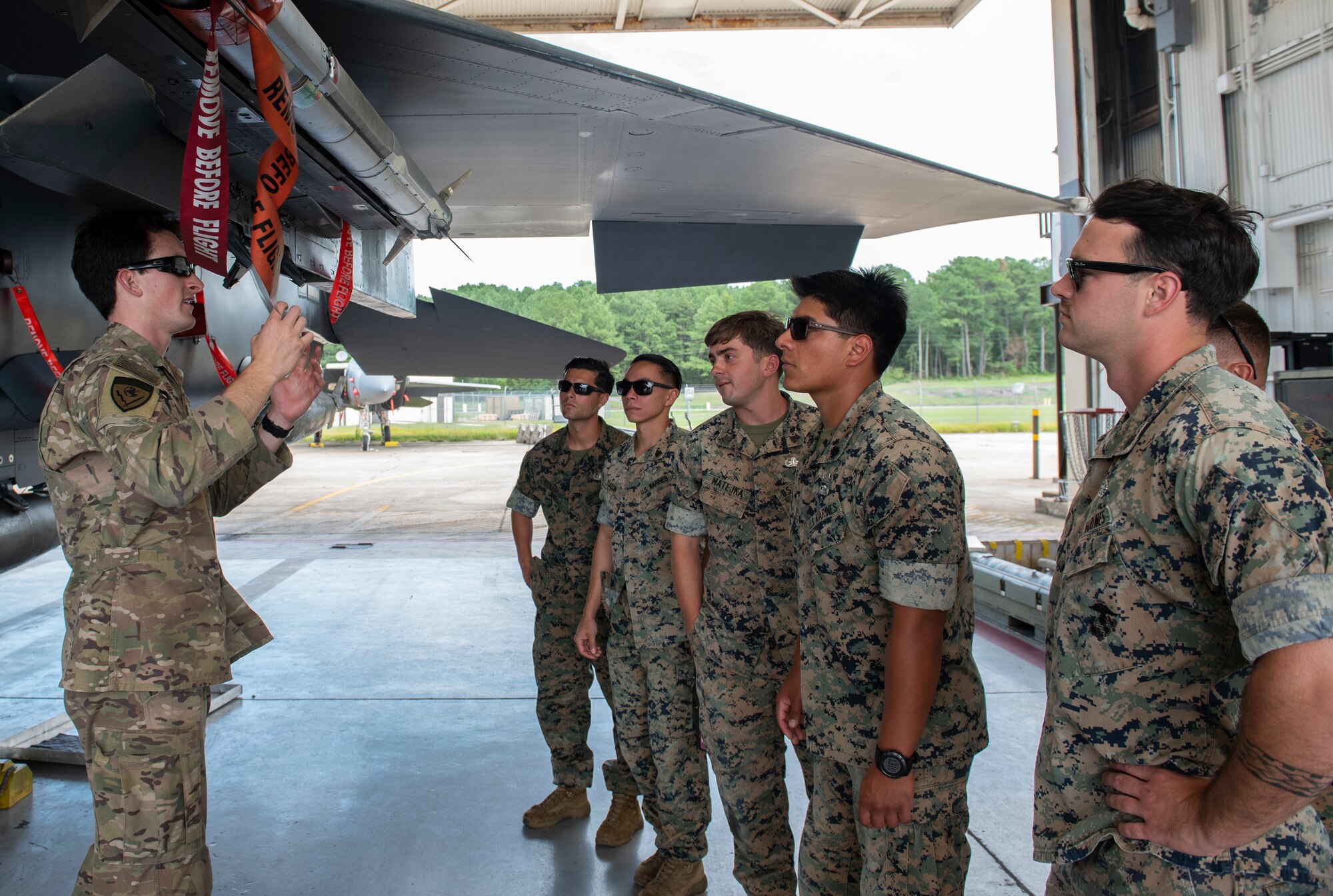 Senior Airman Kyle Heskett, 4th Civil Engineer Squadron explosive ordnance disposal technician, explains how to disarm weapons on an F-15E Strike Eagle to U.S. Marines with EOD assigned to the 8th Engineer Support Battalion, 2nd Marine Logistics Group, August 14, 2019, at Seymour Johnson Air Force Base, North Carolina. Unfamiliar with aircraft, the Marines visited Seymour Johnson AFB to be better prepared for deployments. (U.S. Air Force photo by Senior Airman Kenneth Boyton)