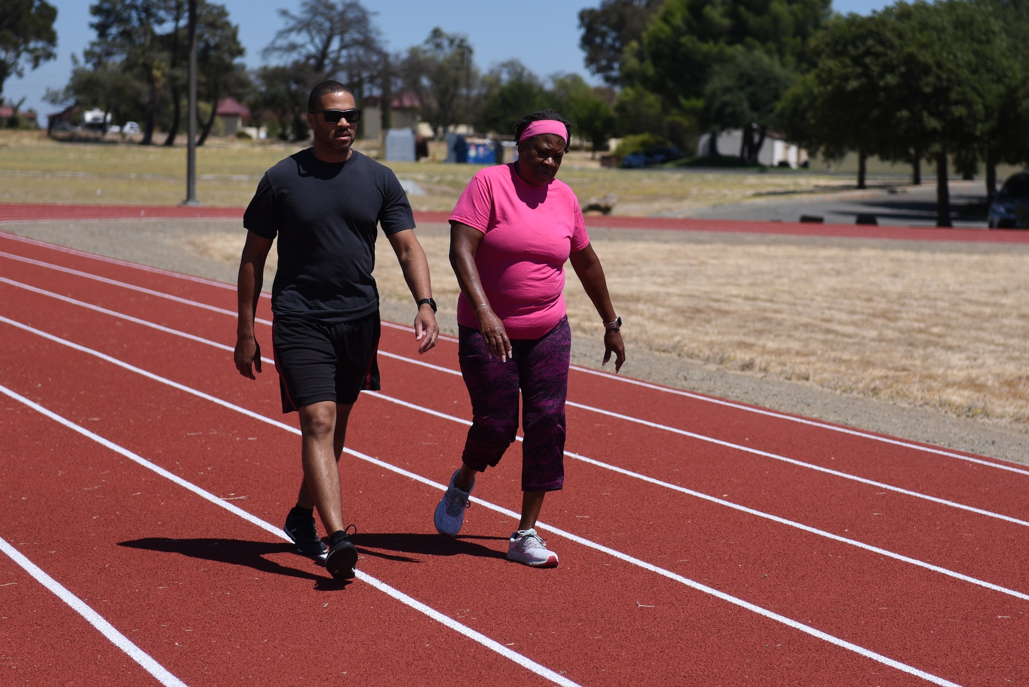 U.S. Air Force Master Sgt. Charlie Belton, 60th Comptroller Squadron budget analyst, and Ophelia Belton, his mother, walk on the newly renovated North Gate Track Aug. 19, 2019, at Travis Air Force Base, California. The tracks recently underwent renovations which included ripping the old track from the ground, placing a solid base of concrete and asphalt, laying down eight layers of rubber padding and painting stripes on the new lanes. (U.S. Air Force photo by Airman 1st Class Cameron Otte)