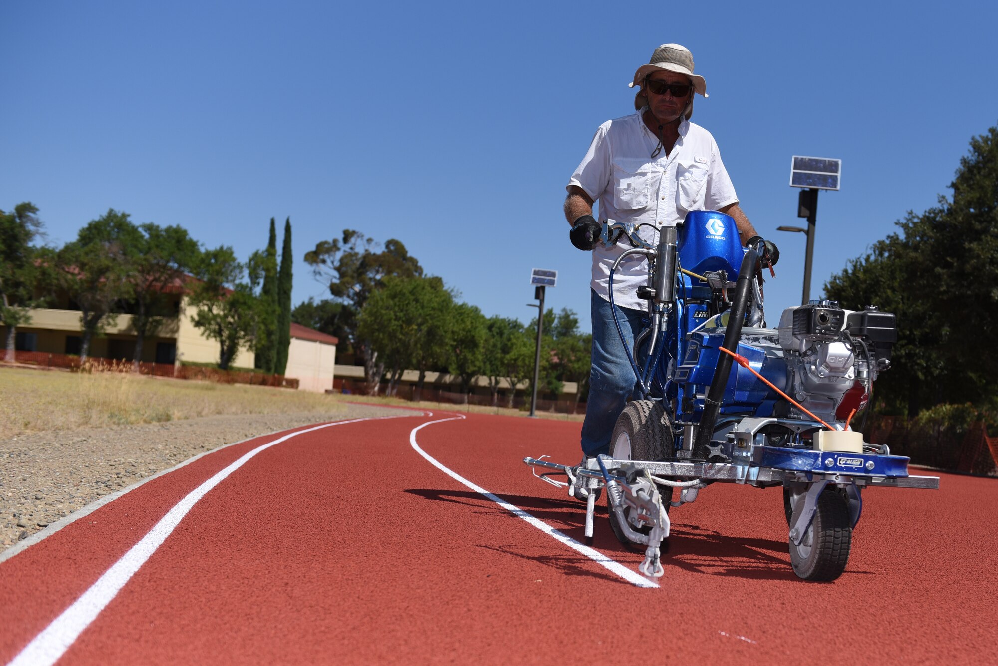 David Wilkins, CMA Construction striper, paints stripes on the Fitness Center Track Aug. 14, 2019, at Travis Air Force Base, California. The tracks recently underwent renovations which included ripping the old track from the ground, placing a solid base of concrete and asphalt, laying down eight layers of rubber padding and painting stripes on the new lanes. (U.S. Air Force photo by Airman 1st Class Cameron Otte)