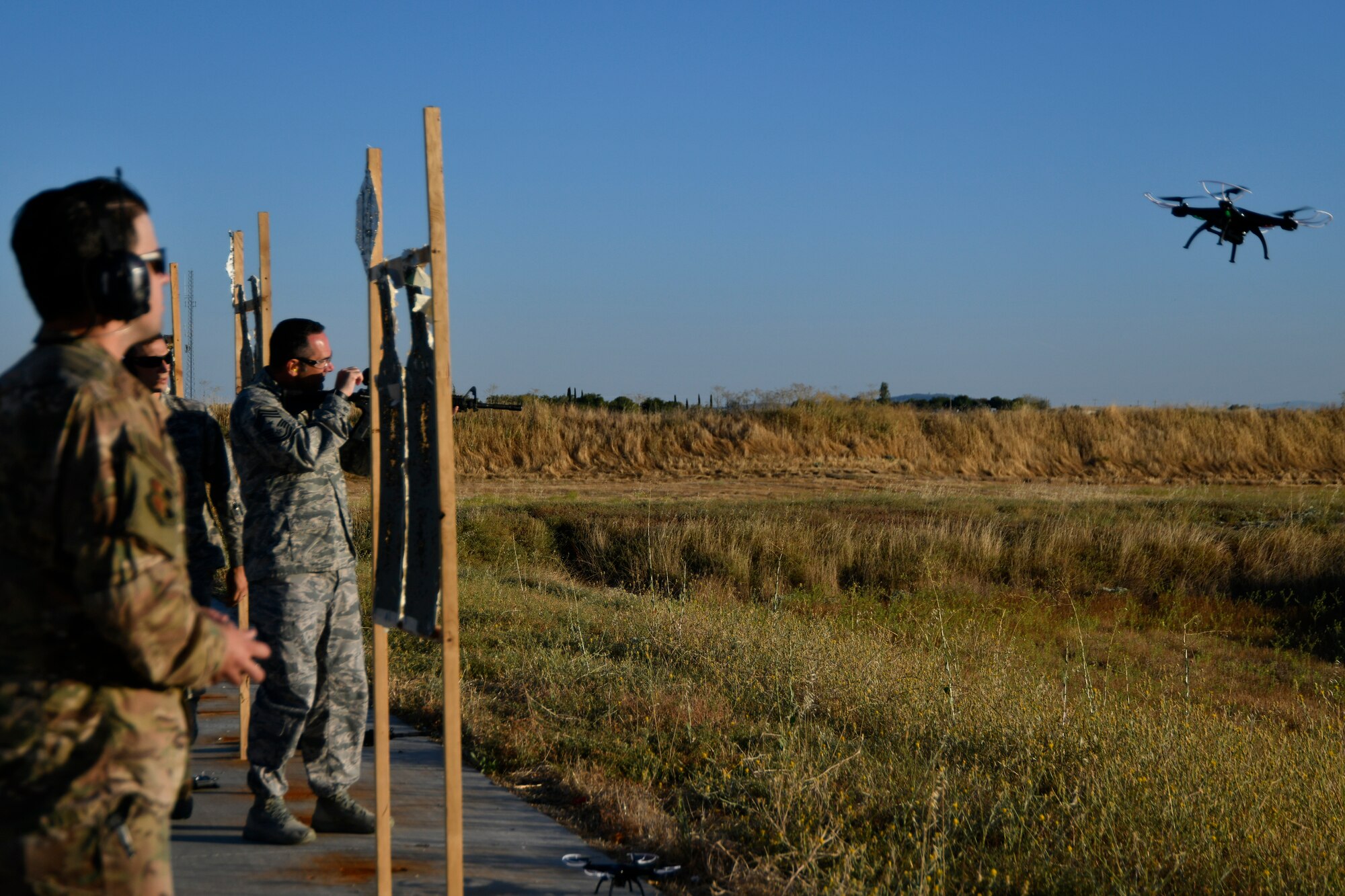 Staff Sgt. Colton Becker, 9th Security Forces Squadron training flight, controls a drone takeoff while Chief Master Sgt. Dustin Hall, 9th Reconnaissance Wing command chief, charges his weapon and sets his sights using the Smart Shooter sighting device during a demonstration at Beale Air Force Base, California, Aug. 14, 2019. The 9th SFS Airmen have been using off the shelf commercial technology to help train and improve how their missions are conducted to protect the installation. (U.S. Air Force photo by Tech. Sgt. Alexandre Montes)