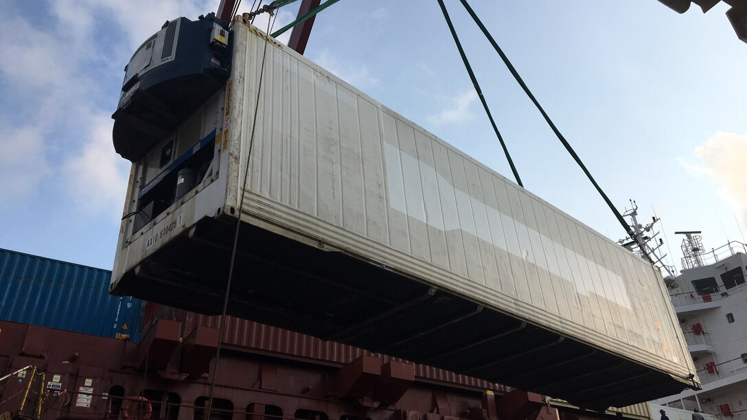 An employee loads a refrigerated shipping container