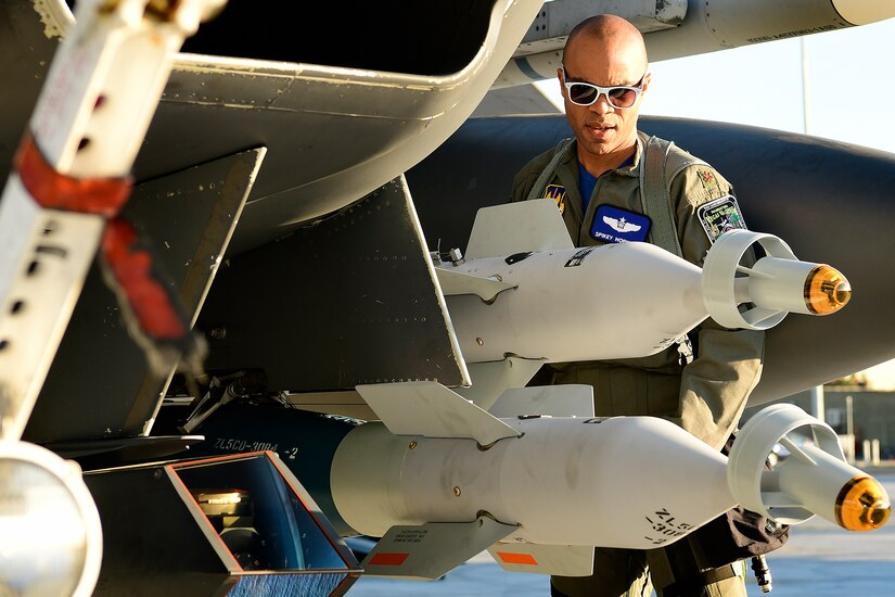 Airmen examines missiles on a jet.