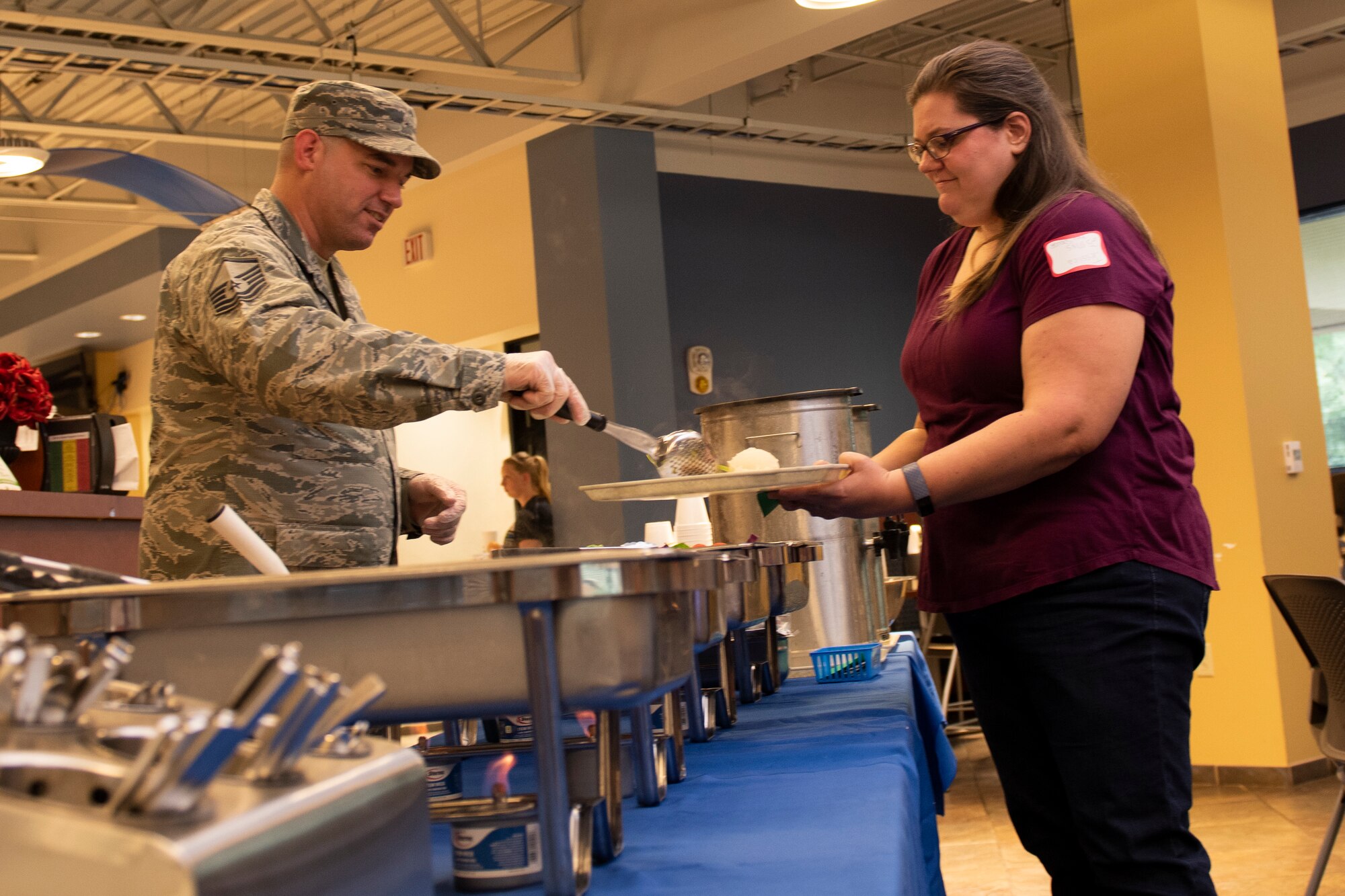 Master Sgt. Kianta Asplund, left, 23d Force Support Squadron NCO in charge of readiness, serves food to a participant during a Deployed Spouse’s Dinner Aug. 20, 2019, at Moody Air Force Base, Ga.  The dinner served as an opportunity for the families of deployed members to bond and provide relief. The mission’s success depends on resilient Airmen and families, who are prepared to make sacrifices with the support of their fellow Airmen, local communities and leadership. (U.S. Air Force photo by Airman Elijah M. Dority)