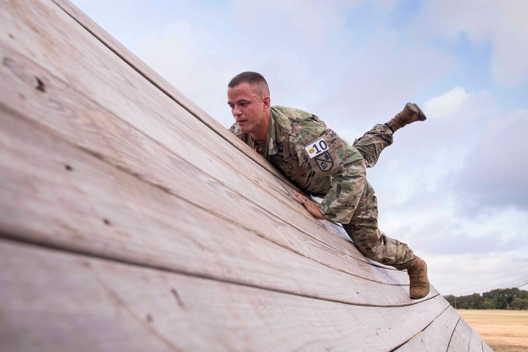 A soldier climbs over a wall.