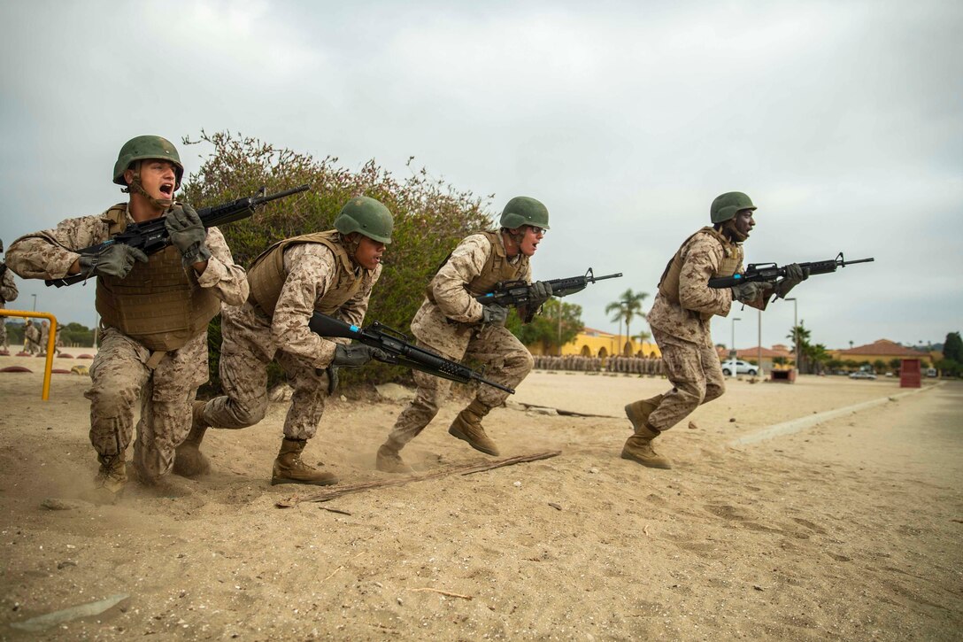 Four service members run with weapons.