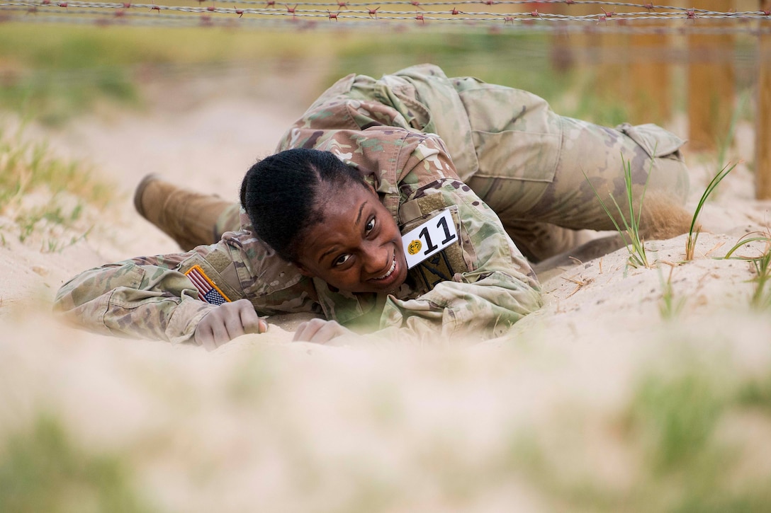 A soldier crawls under barb wire.