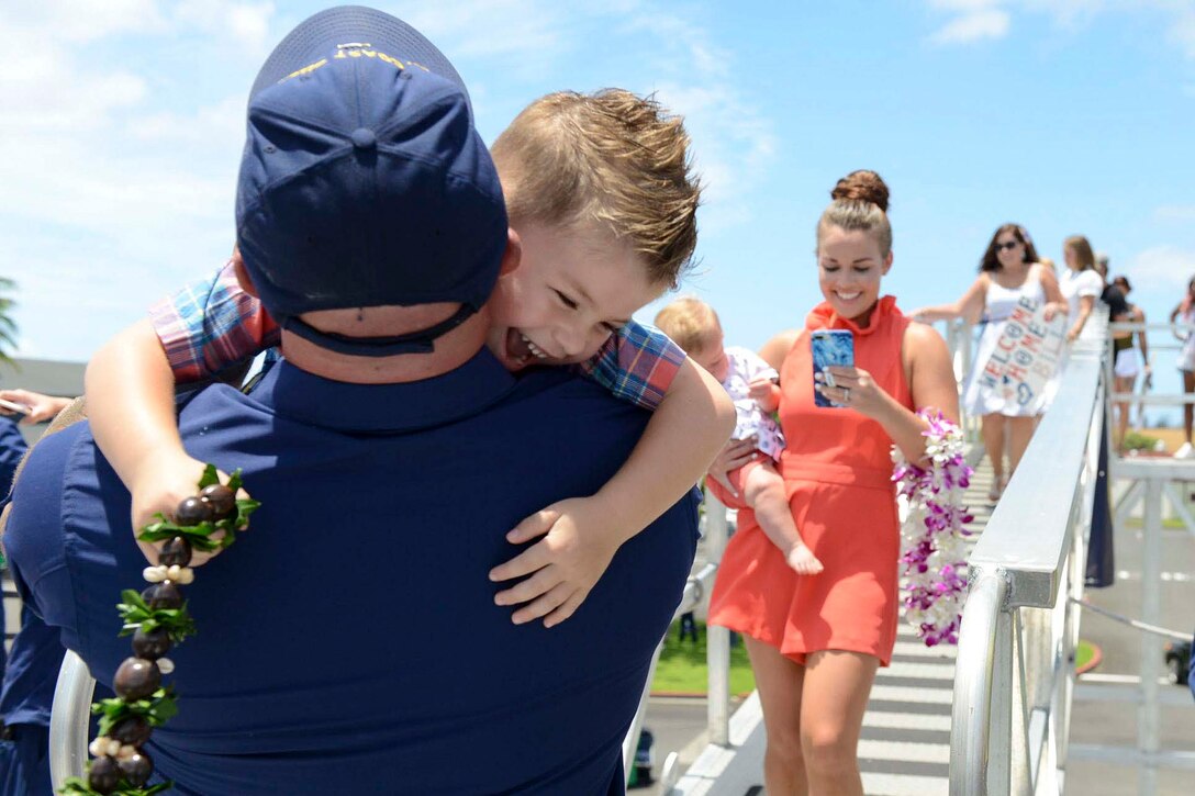 A Coast Guardsman hugs his a child.