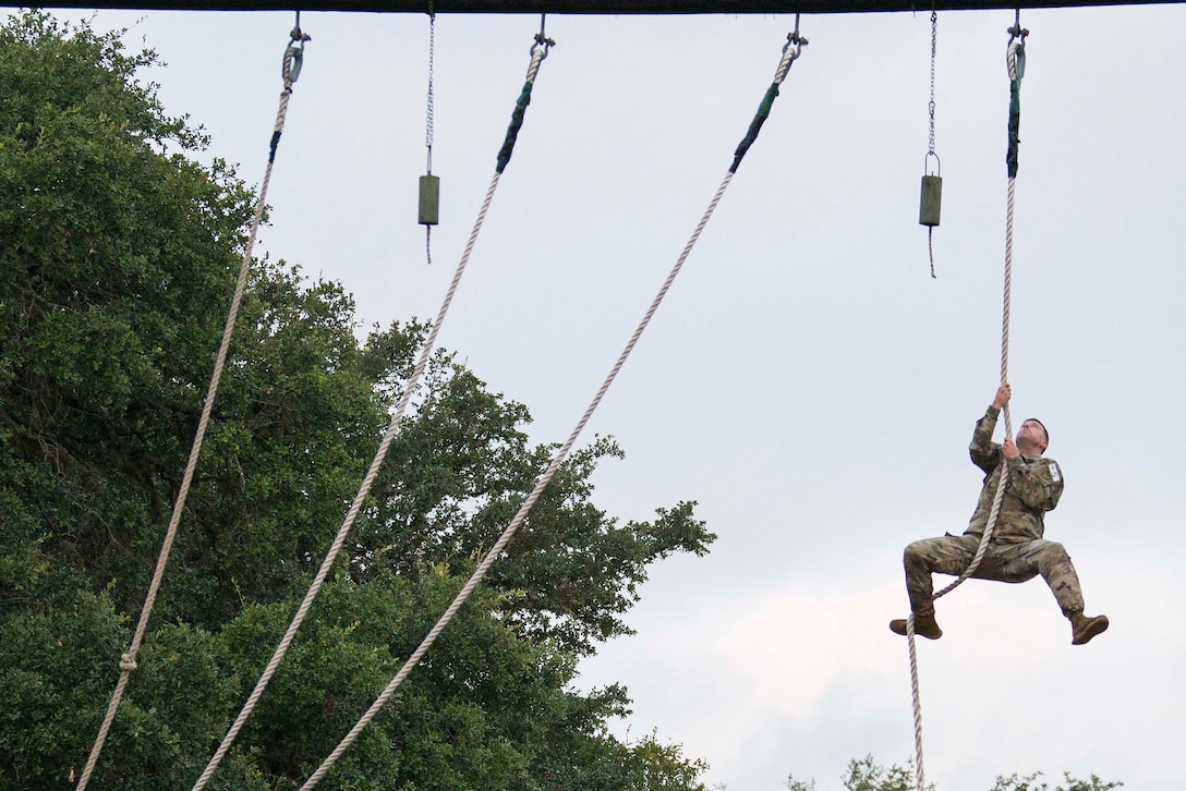 A soldier climbs a rope.