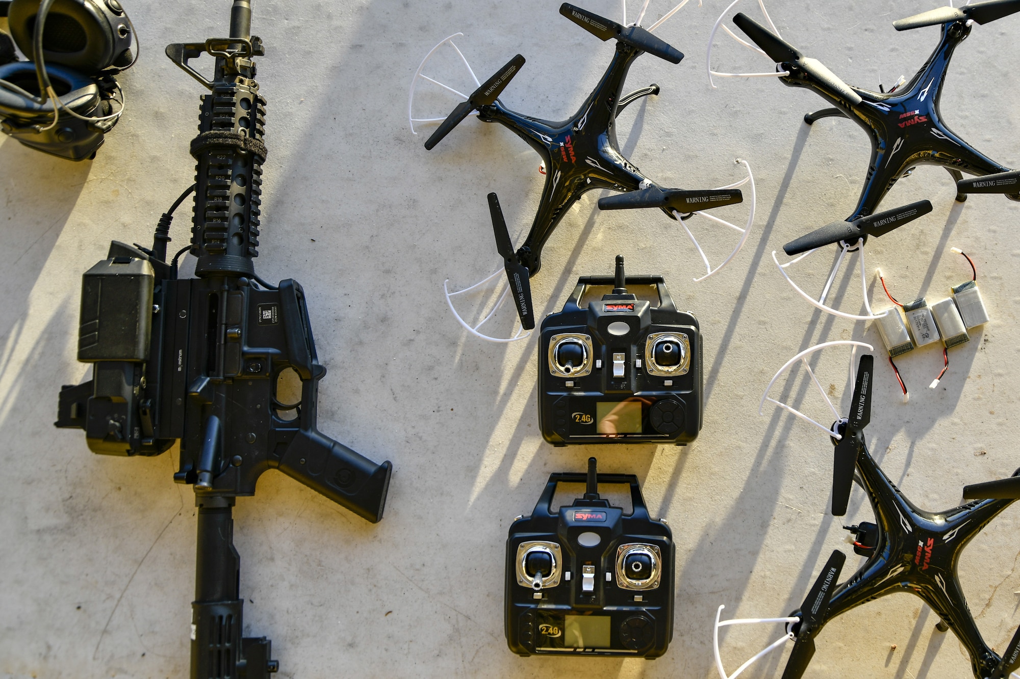 A M4 Carbine rifle donning the Smart Shooter sighting device lays next to drones that will be used as moving targets for 9th Reconnaissance Wing leadership at Beale Air Force Base, California, Aug. 14, 2019. The sighting device attaches to the weapon and locks on then fires to neutralize its target with or without movement. The device is also being used to limit friendly fire as the weapon cannot be fired unless it is purposely locked on. (U.S. Air Force photo by Tech. Sgt. Alexandre Montes)