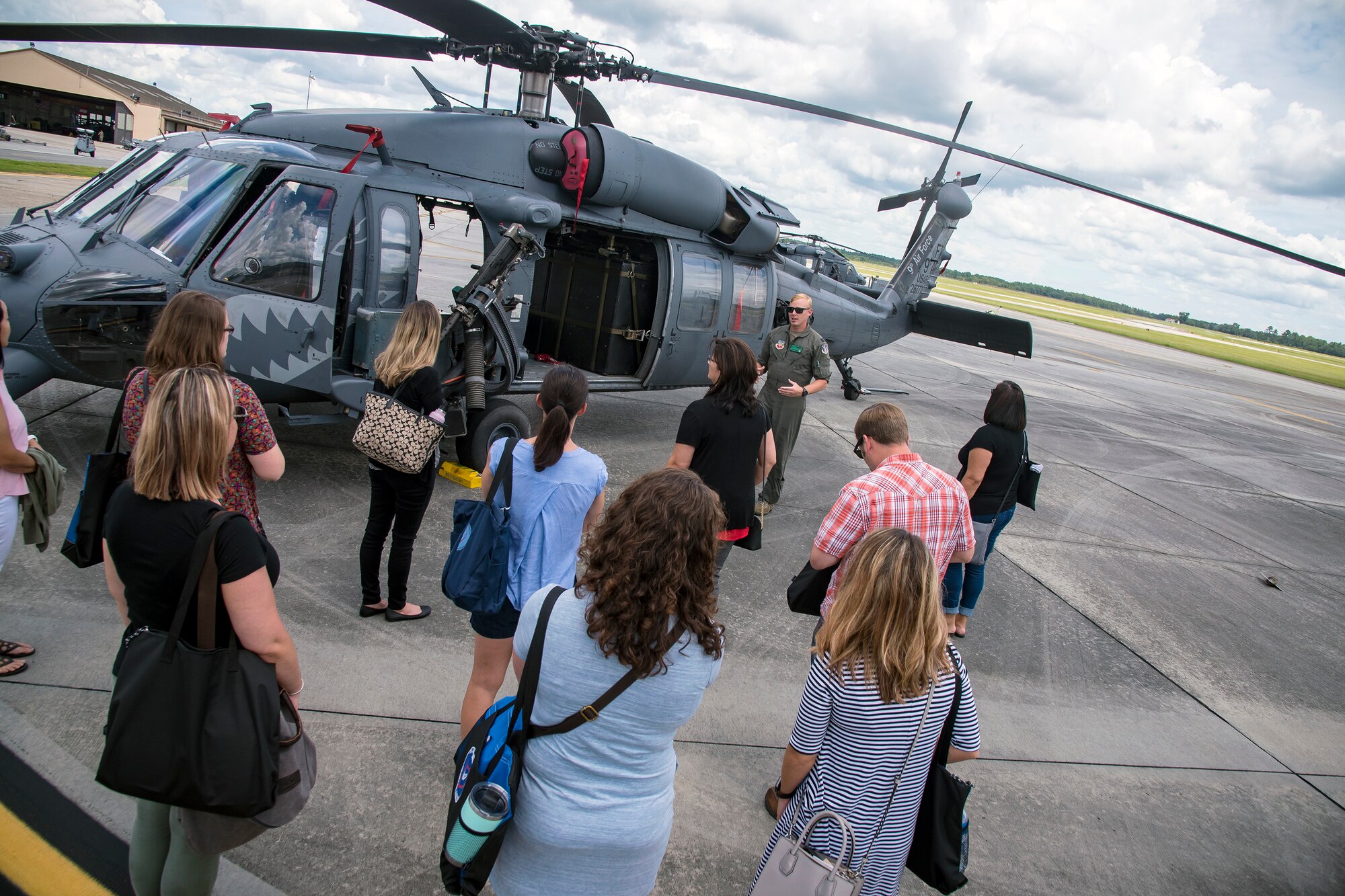 Team Moody spouses observe an HH-60G Pave Hawk helicopter during a Heart Link spouse orientation Aug. 21, 2019, at Moody Air Force Base, Ga. The orientation is geared toward providing all spouses and family members with the necessary support and information to ensure that they are aware of the resources available to them such as: Tricare, legal assistance, Airman and Family Readiness Center and financial assistance. During the orientation, spouses were given a static display tour to better familiarize them with the aircraft and mission here. (U.S. Air Force photo by Airman 1st Class Eugene Oliver)