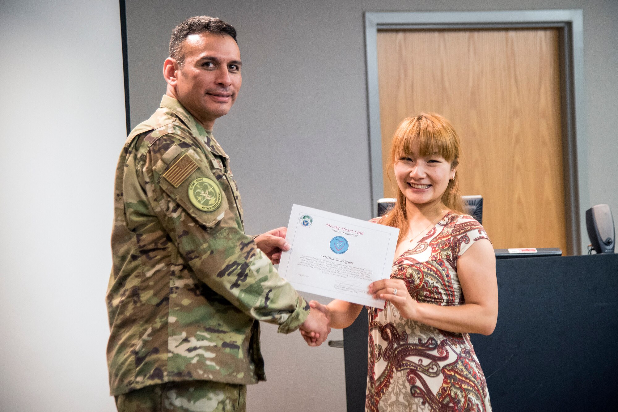 Col. Benjamin Conde, left, 23d Wing vice commander, coins a Team Moody spouse during a Heart Link spouse orientation Aug. 21, 2019, at Moody Air Force Base, Ga. The orientation is geared toward providing all spouses and family members with the necessary support and information to ensure that they are aware of the resources available to them such as: Tricare, legal assistance, Airman and Family Readiness Center and financial assistance. (U.S. Air Force photo by Airman 1st Class Eugene Oliver )