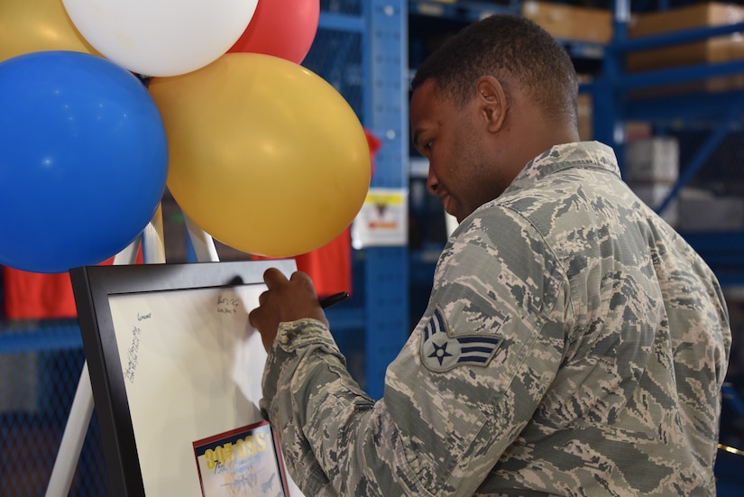 An Airman signs a 75th anniversary poster during the 305th Operations Support Squadron Silver Carpet Day event, August 16, 2019 at Joint Base McGuire-Dix-Lakehurst, N.J. The 305th OSS celebrated the 75th Anniversary of the 305th OSS heritage, which was united from two squadrons – the 305th Airdrome Squadron and the 305th OSS. (U.S. Air Force photo by Staff Sgt. AJ Hyatt)