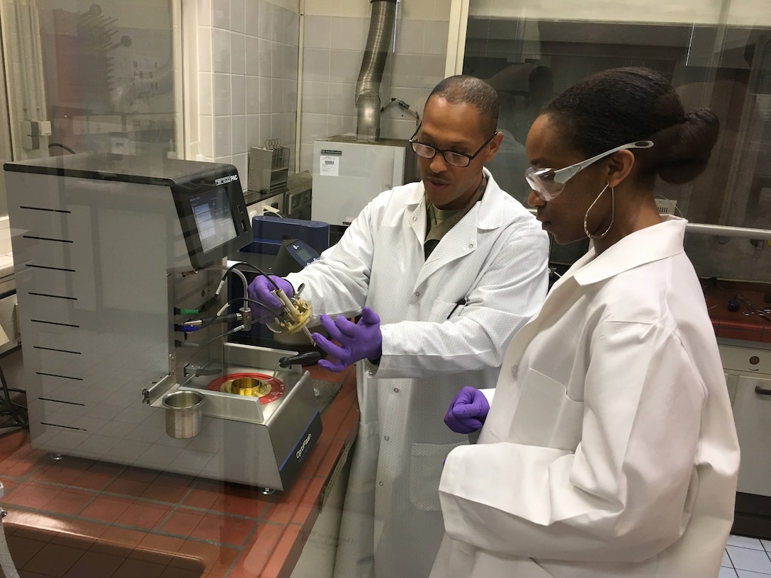 Two people inspect a fuel sample.