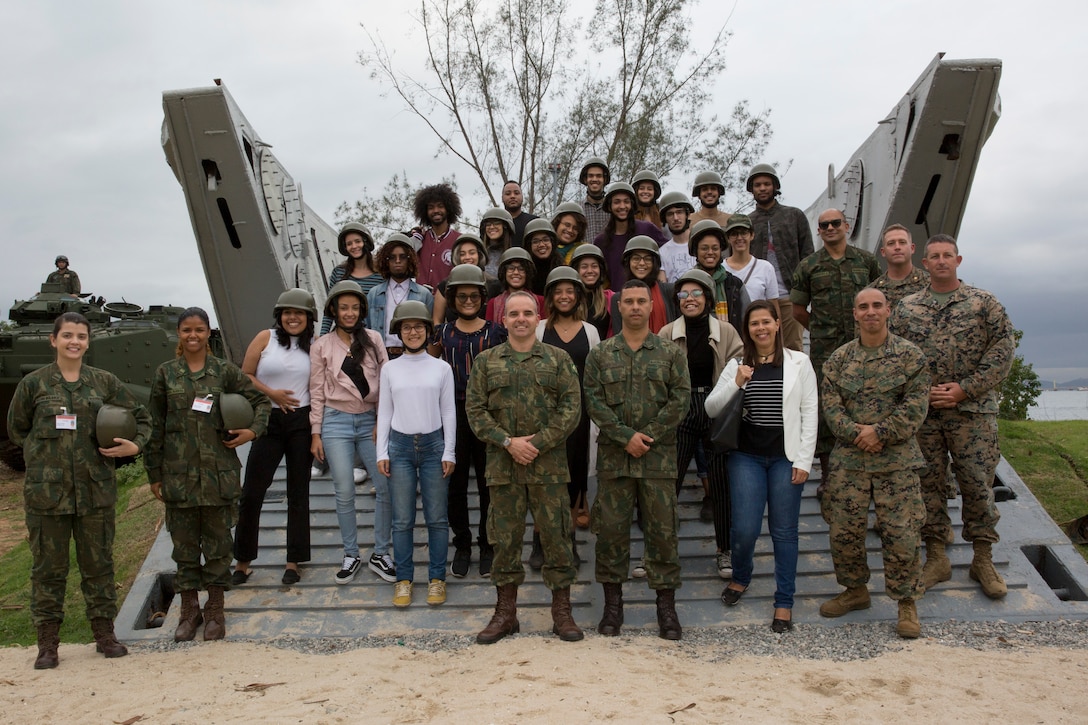 U.S. Marines, Brazilian Marines and students from Universidade Federal do Rio de Janeiro take a group photo during a tour at Ilha do Governador during UNITAS LX, Aug. 21, 2019. UFRJ students toured the base to better understand military capabilities and relations. UNITAS is the world's longest-running, annual exercise and brings together multinational forces from 11 countries to include Brazil, Colombia, Peru, Chile, Argentina, Ecuador, Panama, Paraguay, Mexico, Great Britain and the United States. The exercise focuses in strengthening the existing regional partnerships and encourages establishing new relationships through the exchange of maritime mission-focused knowledge and expertise during multinational training operations.