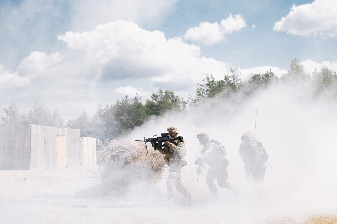 Soldiers move toward a target through smoke.