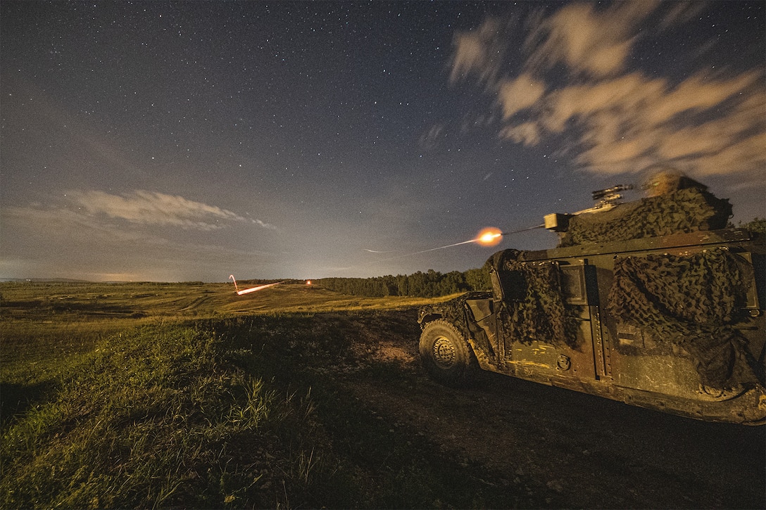 A soldier fires a weapon at night.