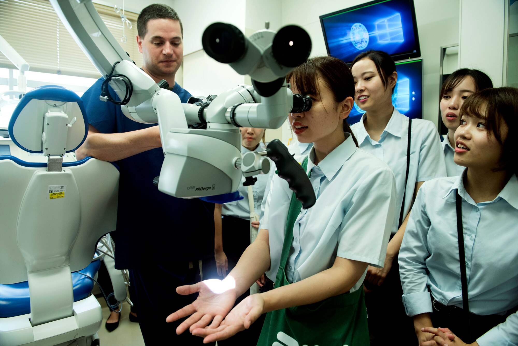 Maj. David Weyh, 18th Dental Squadron endodontist, shows off a dental microscope used for root canal procedures and surgeries to Miyu Nakamura, a dental hygienist student, during White Dental Clinic's tour of the 18th DS clinic, Aug. 16, 2019.