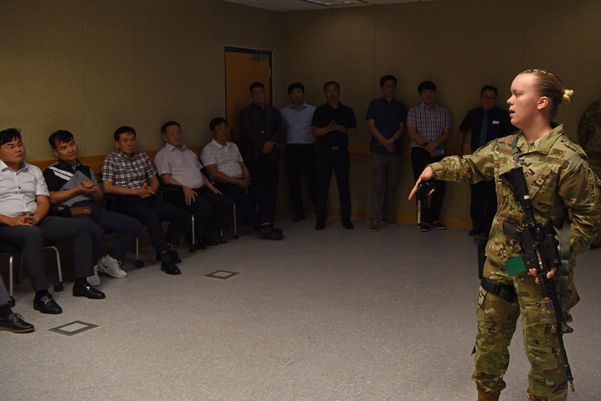 U.S. Air Force Senior Airman Katelynn Hagadorn, 8th Security Forces Squadron multiple interactive learning objectives trainer, showcases an M-9 handgun to Korean National Police Gunsan City branch members at Kunsan Air Base, Republic of Korea, Aug. 20, 2019. Hagadorn showcased the equipment security forces uses on a virtual reality training simulator. (U.S. Air Force photo by Staff Sgt. Joshua Edwards)