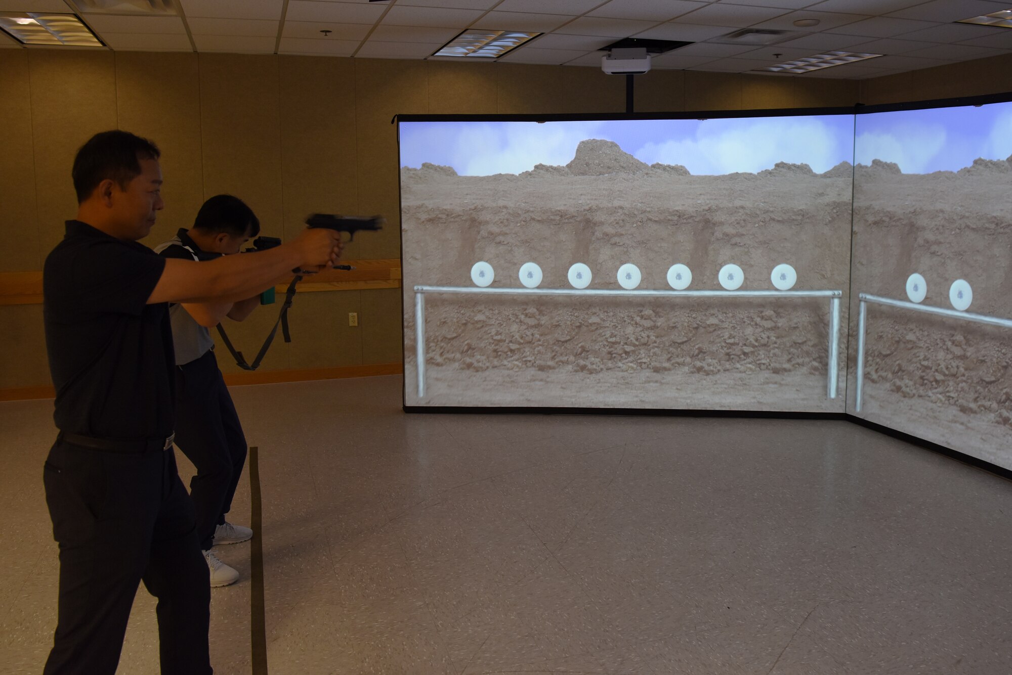 Two members of the Korean National Police Gunsan City branch test a weapon simulation system at Kunsan Air Base, Republic of Korea, Aug. 20, 2019. The KNP received the chance to test out the equipment the 8th Security Forces Squadron use on a daily basis. (U.S. Air Force photo by Staff Sgt. Joshua Edwards)