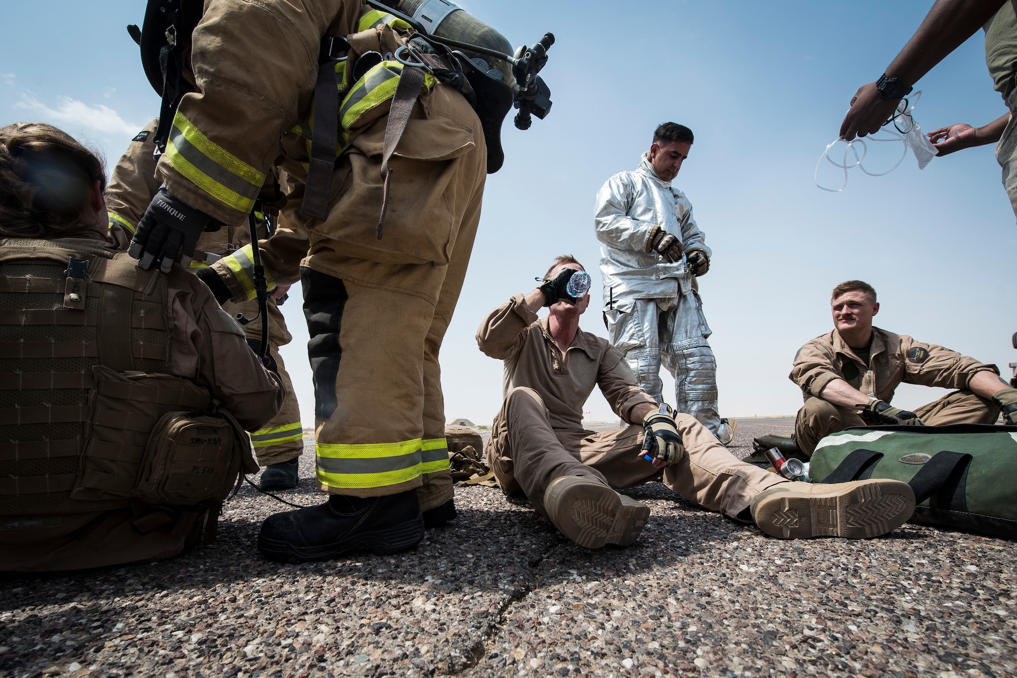 Exercise participants hydrate while being treated during an airfield exercise at Ahmed al-Jaber Air Base, Kuwait, Aug. 16, 2019. Several emergency service vehicles arrived on-scene and simulated putting out the fire in the MV-22 Osprey then providing immediate medical care to the victims. Firefighters and medical personnel included Airmen, Marines and Sailors. (U.S. Air Force photo by Senior Airman Lane T. Plummer)