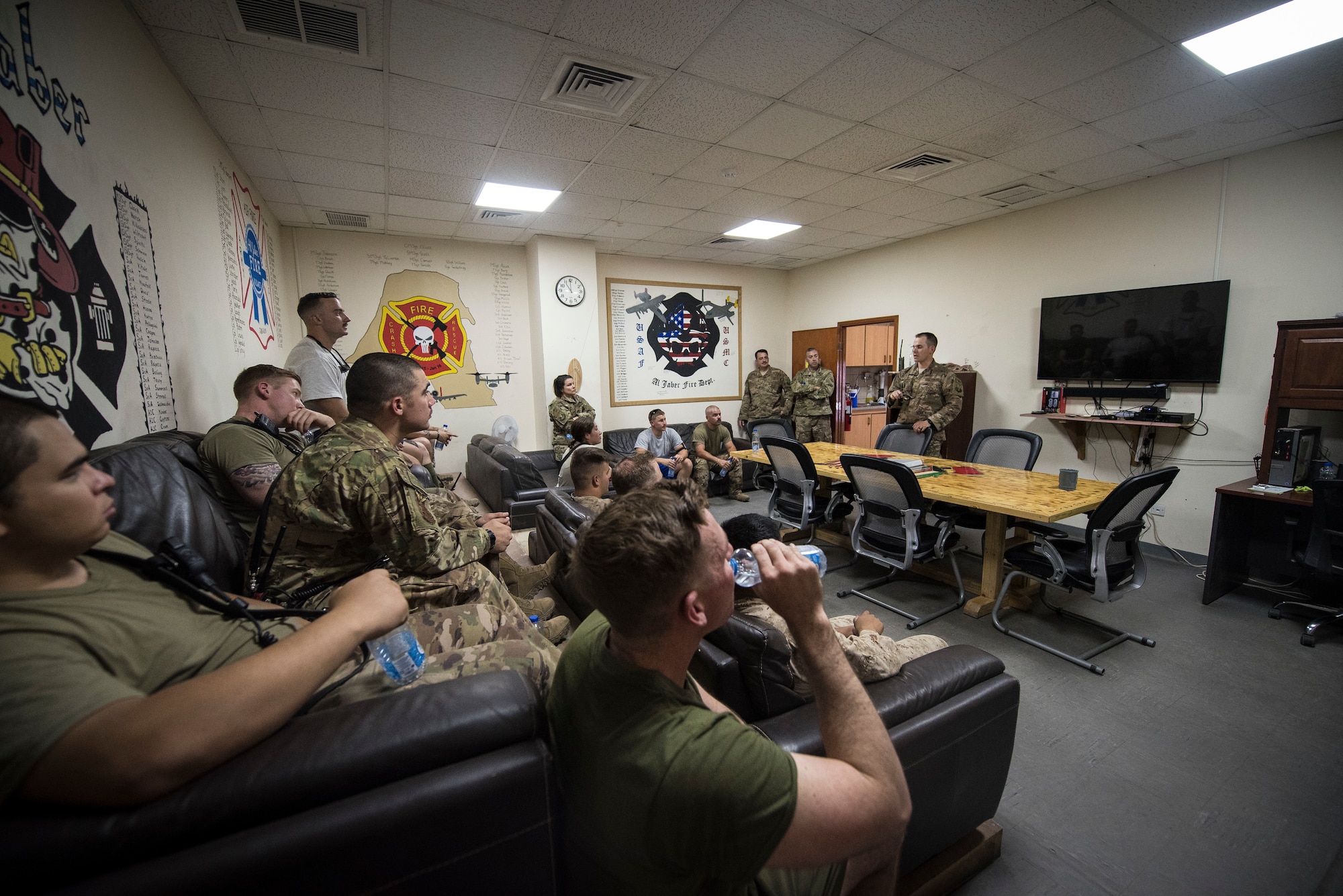 U.S. Airmen and Marine Corps firefighters participate in an after-action report meeting following an airfield exercise at Ahmed al-Jaber Air Base, Kuwait, Aug. 16, 2019. After training, the firefighters will conduct a meeting to discuss how the exercise went and ways to improve their response. (U.S. Air Force photo by Senior Airman Lane T. Plummer)