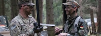 U.S. Army Maj. Sean Hill, observer coach/trainer for the Joint Multinational Readiness Center, converses with German Lt. Col. Gunter Flach, officer for 1st Armored Engineer Battalion, at the (German) 21st Armoured Brigade Tactical Operations Center at Hohenfels, Germany, during the distinguished visitors portion of exercise Allied Spirit X, April 9, 2019.