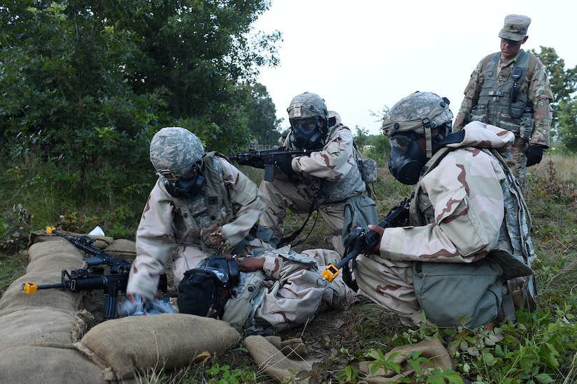 An Observer Coach/trainer assigned to 1-340th Training Support Battalion, 85th U.S. Army Reserve Support Command, looks on as Soldiers assigned to the 414th Transportation Company, Orangeburg, South Carolina, provide medical attention to a wounded Soldier during a complex attack with small arms weapons on their base at dusk on August 17, 2019 at Combat Support Training Exercise 86-19-04 at Fort McCoy, Wisconsin.