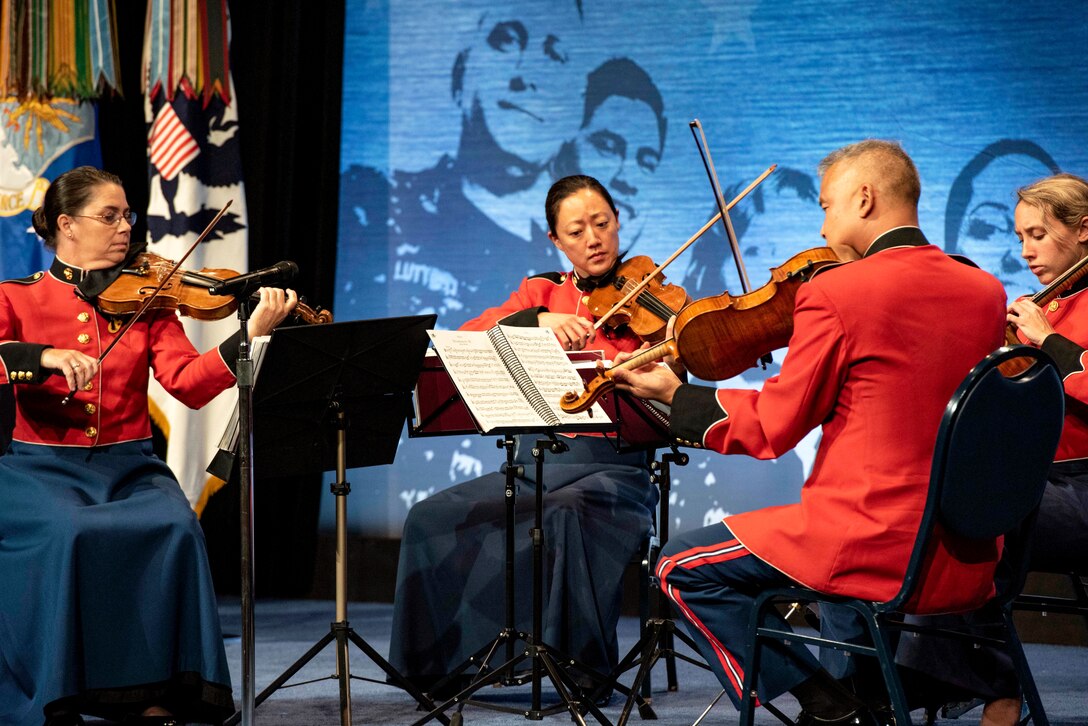 A Marine Corps string quartet performs on a stage with a blue background.