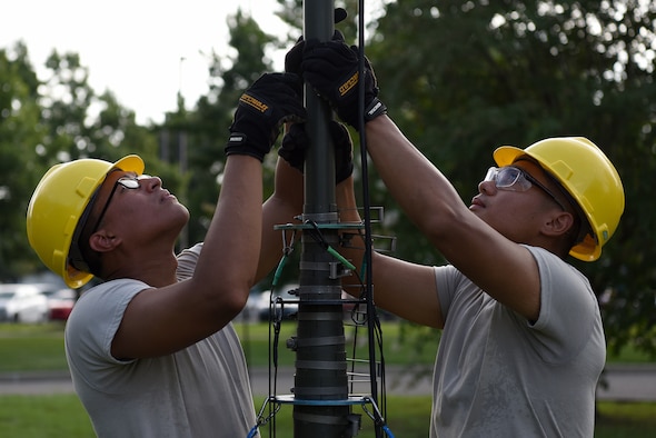 U.S. Air Force Airmen 1st Class Erlin Hernandez and Samuel Sein, 338th Training Squadron Radio Frequency Transmission Systems students, set up an ultra high frequency antenna outside of Jones Hall on Keesler Air Force Base, Mississippi, August 12, 2019. The course has been transitioning to an active learning approach where students teach their peers the course material while an instructor monitors. (U.S. Air Force photo by Senior Airman Suzie Plotnikov)