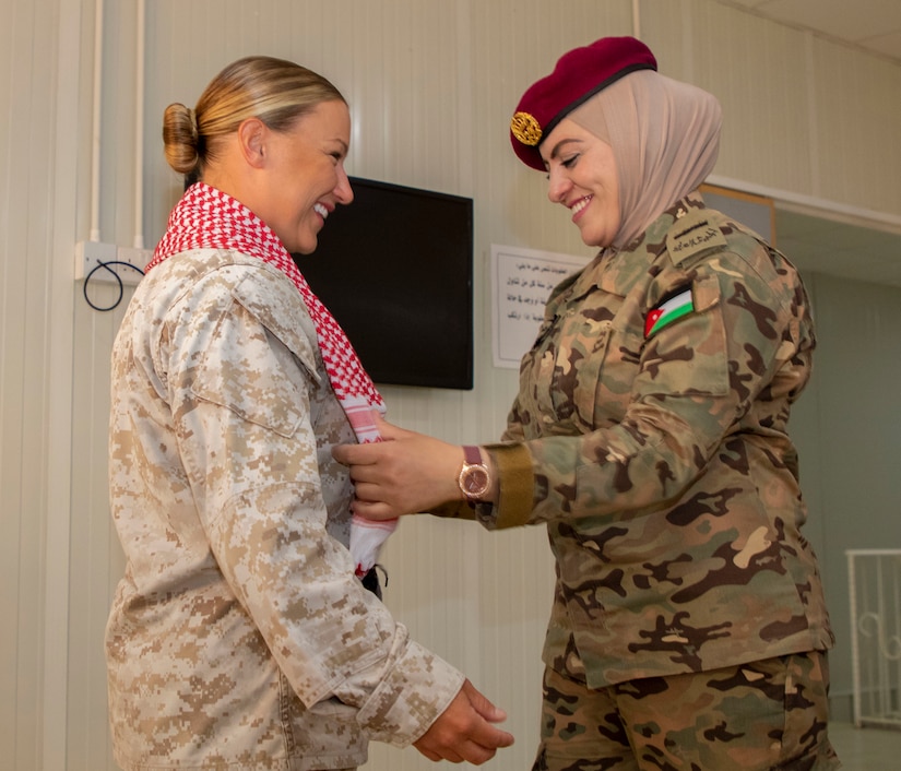 Jordan Armed Forces-Arab Army 1st Sgt. Haneén Attiat (right), with Quick Reaction Force Female Engagement Team (FET), adorns the shoulders of U.S. Marine Capt. Katie Modzelewski, with 11th Marine Expeditionary Unit FET, with a scarf as a gift of appreciation following the closing ceremony for the subject matter exchange between the two countries August 7, 2019. The U.S. is committed to the security of Jordan and to partnering closely with JAF to meet common security challenges.
