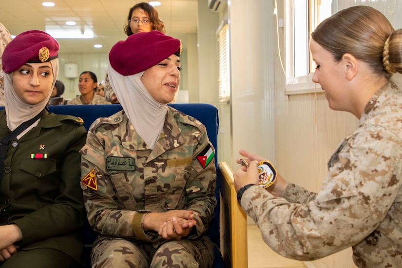 Jordan Armed Forces-Arab Army Quick Reaction Force (FET) member (left) smiles in surprise as U.S. Marine Cpl. Danielle Grimshaw, with 11th Marine Expeditionary Unit (FET), gives her a coin as a token of appreciation following the closing ceremony for the subject matter exchange between the two countries August 7, 2019. The U.S. is committed to the security of Jordan and to partnering closely with JAF to meet common security challenges.
