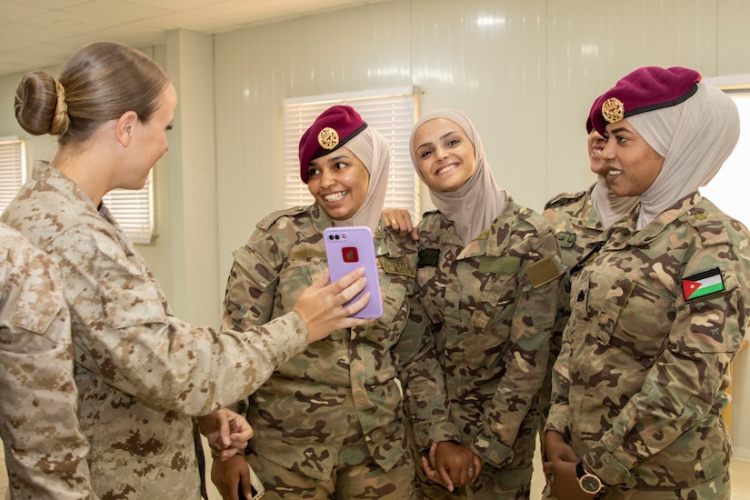 U.S. Marine Cpl. Danielle Grimshaw (left), with 11th Marine Expeditionary Unit (FET), shows members of the Jordan Armed Forces-Arab Army Quick Reaction Force (FET) the selfie they took after the closing ceremony of the subject matter exchange between the two countries August 7, 2019. The U.S. is committed to the security of Jordan and to partnering closely with JAF to meet common security challenges.
