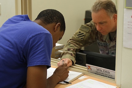 Sgt. Curtis D. Holder, 247th Finance Management Support Detachment, helps with filling out a form, at Camp Arifjan, Kuwait, Aug. 19, 2019.
