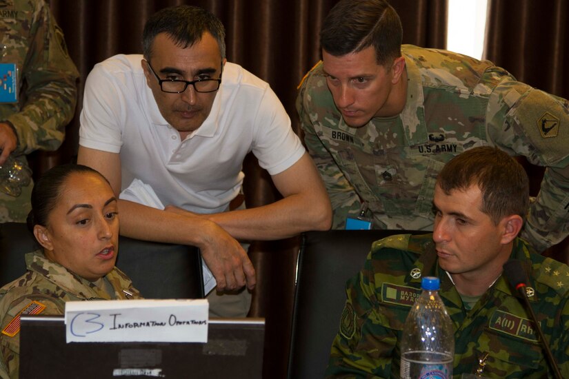 From left, Army Staff Sgt. Myrna Bistros, intelligence support to information operations for exercise Regional Cooperation 2019, 303rd Information Operations Battalion, 151st Theater Informations Operations Group, United States Civil Affairs and Psychological Operations Command; Daler Djavadov, Tajikistan linguist for RC19; Army Sgt. 1st Class Jeremy Brown, operations sergeant major for RC19, 51st Troop Command, Massachusetts Army National Guard; and Tajik Army Capt. Nope Muhammad, information operations, Task Force Patriot; all discuss exercise operations during Regional Cooperation 2019 at Dushanbe, Tajikistan, August 10, 2019. Exercise Regional Cooperation is an annual exercise to help strengthen military-to-military relationships between the United States and partners in Central and South Asia. The exercise enhances regional security and stability among the participating nations.