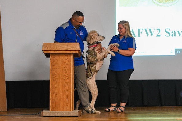 Master Sgt. Jose Rijos, noncommissioned officer in charge of domestic operations, Massachusetts Air National Guard and Wounded Warrior ambassador, stands on stage with his service dog Cairo and his wife, Yadira Rijos, at the Hanscom Air Force Base theater, Aug. 22. Both Wounded Warrior Program ambassadors, Jose and Yadira spoke on their experiences dealing post-traumatic stress as a family in hopes to dismantle the stigma surrounding mental health. (U.S. Air Force photo by Mark Herlihy)