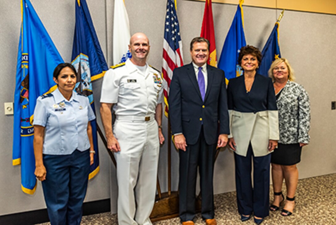 Five adults gather for a group photograph.