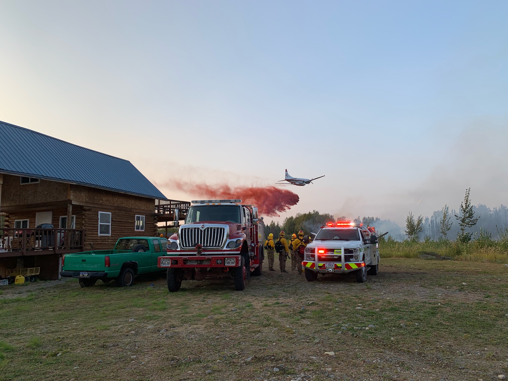 Joint Base Elmendorf-Richardson firefighters wait to re-engage fire suppression efforts while a Candian aircraft drops flame retardant on the McKinley Fire near mile marker 90.5 along the Parks Highway in Alaska, Aug. 18, 2019. The Matanuska-Susitna area fire management officer requested assistance from the JBER taskforce, which immediately responded and fought the fire alongside local and state firefighters.