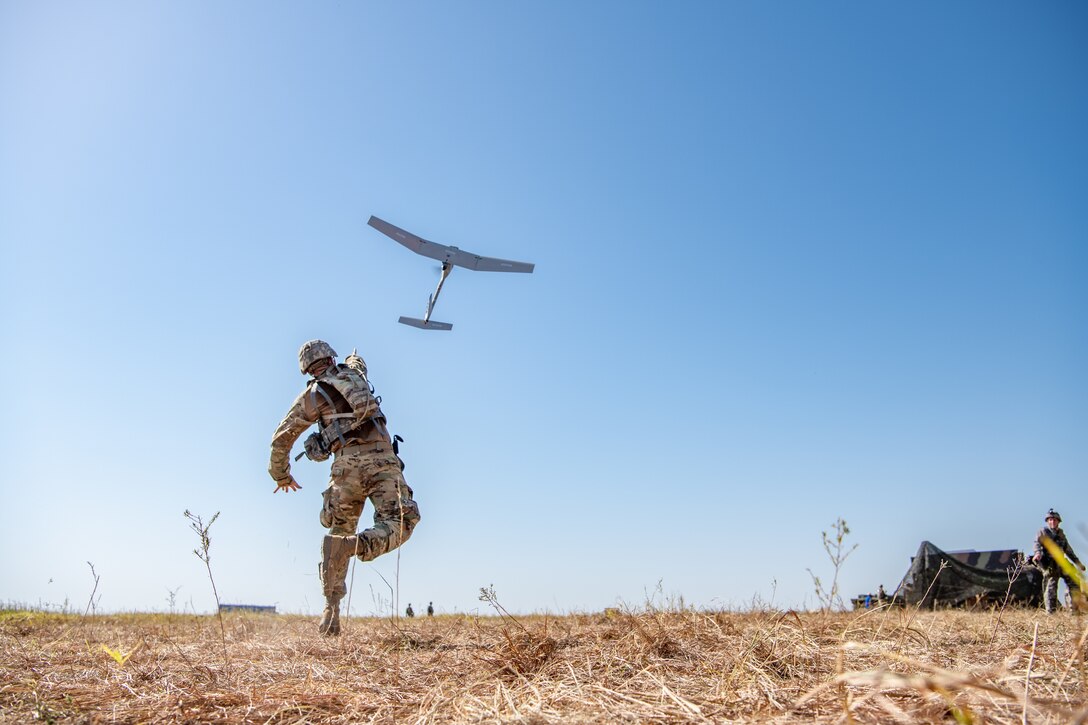 A soldier throws a small aircraft into the sky.