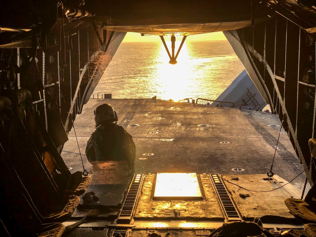 A U.S. Marine with the 22nd Marine Expeditionary Unit observes the sunrise from the back of a CH-53E Super Stallion prior to departure from the Wasp-class amphibious assault ship USS Kearsarge (LHD-3) March 29, 2019.
