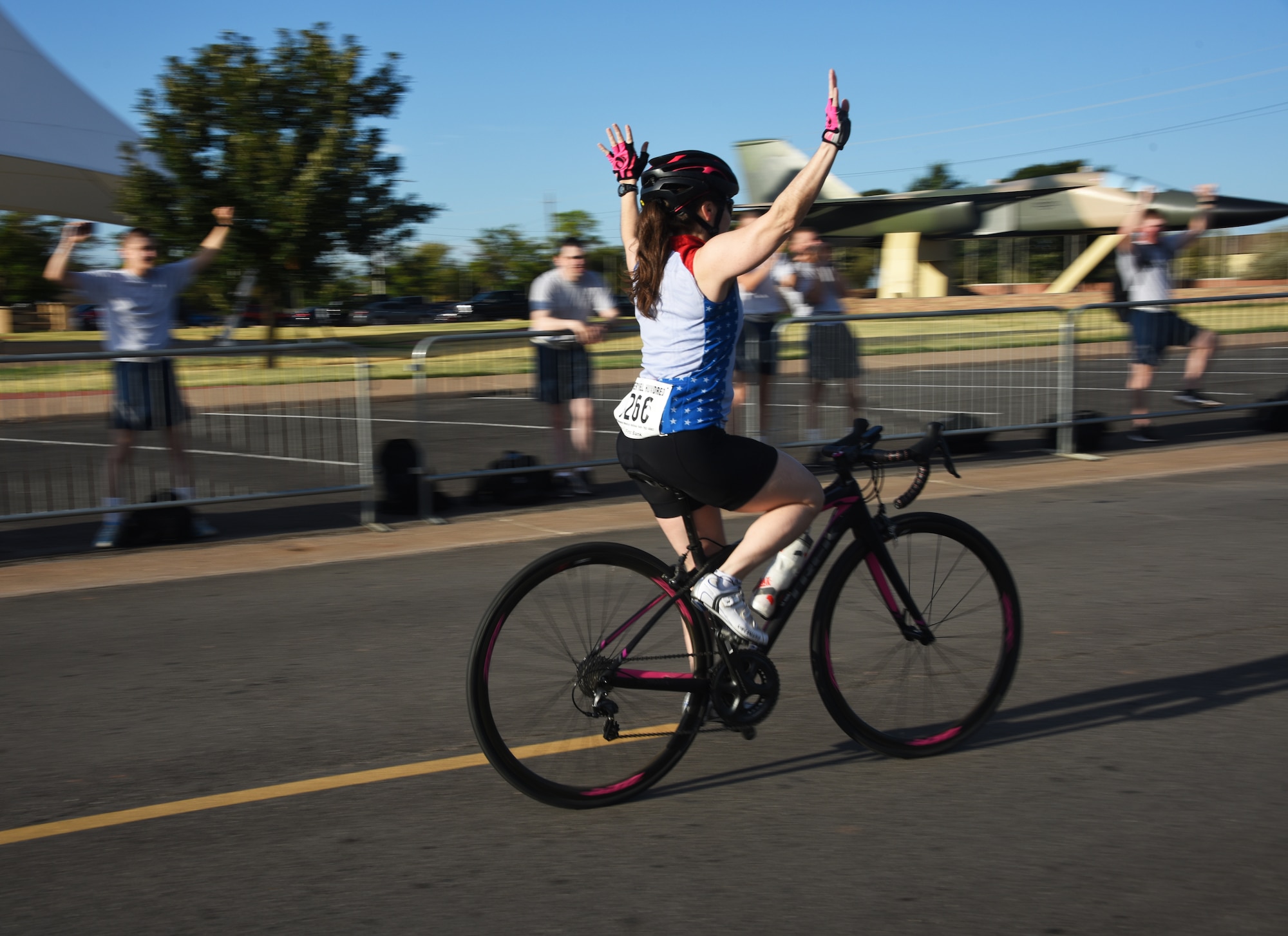 Hotter'N Hell cyclists cruises down Airmen’s Alley with her hands in the air