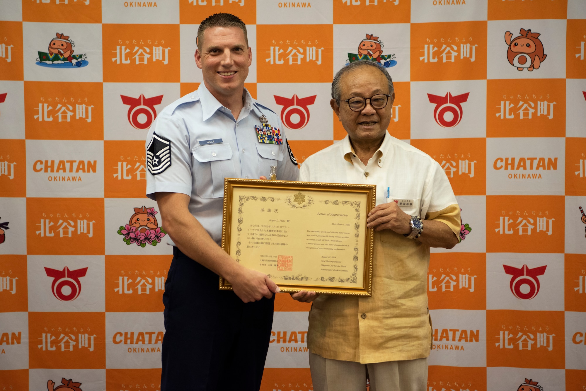 Two men smile and hold up a framed certificate.